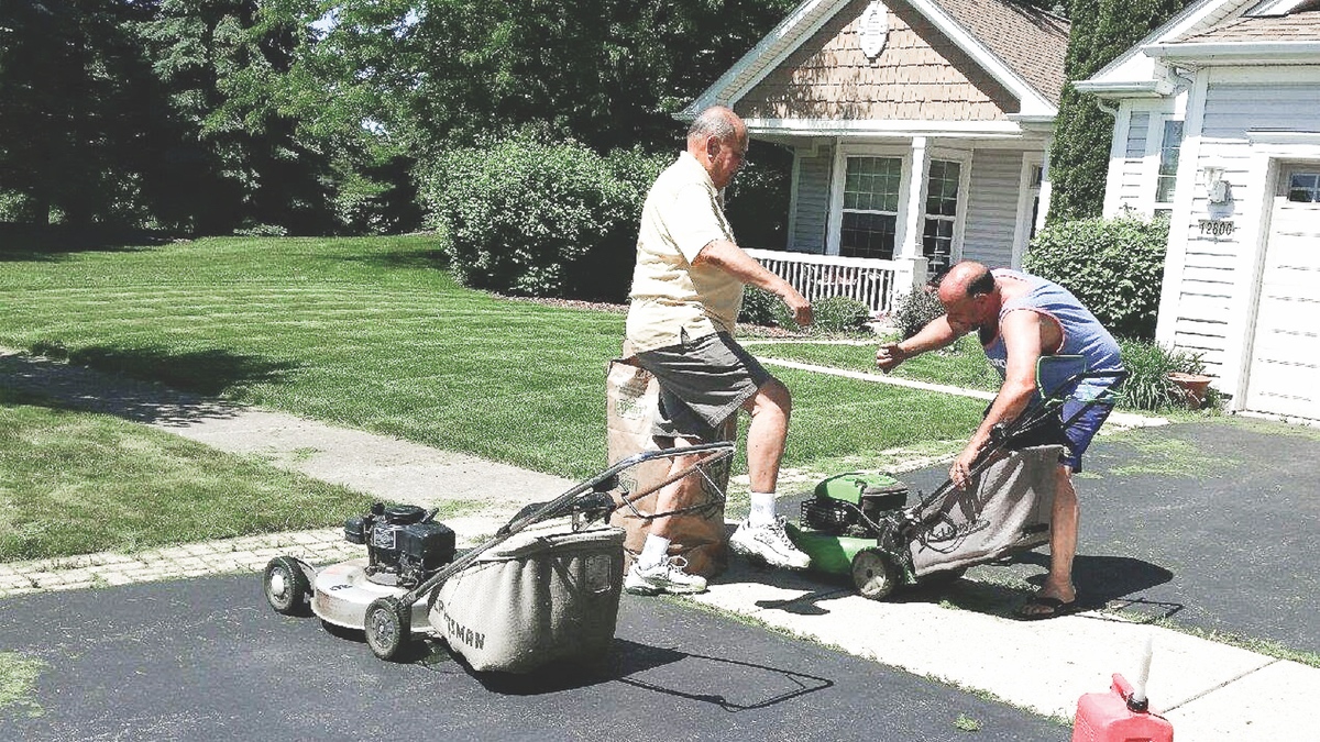 Ron Tampa (left) and his son Ronnie giving the lawns that satisfying just-cut look. (Photo by Christine Such/Sun Day)