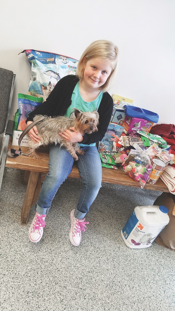 Top: Victoria with Mom and Basil.   Above: “I want to make sure the kitties are healthy,” says Victoria, with shelter dog Sassy and surrounded by donations. (Photos provided)