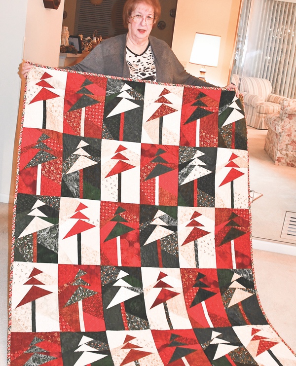 Darlene Hagner holds up a recent holiday-theme quilt.