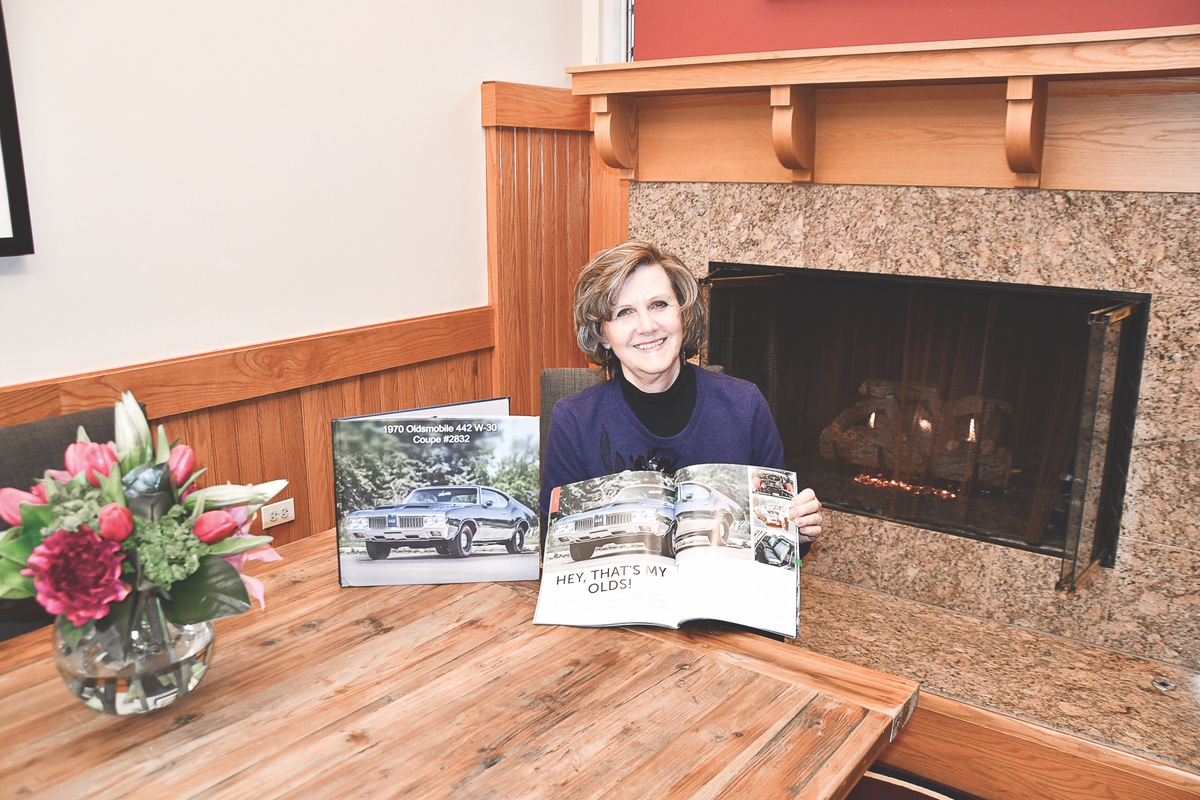 Gagainis with a book created by the current owner of the Oldsmobile, showcasing the history of the car. (Photo by Christine Such/Sun Day)