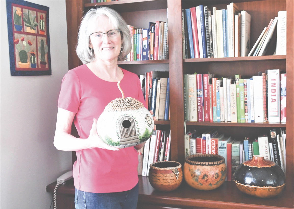 Judy Escallier holding a gourd with a shake roof out of seeds.