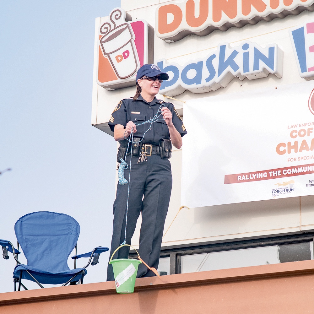 Huntley Police Department SGT Amy Williams hoists up a donation for the Illinois Special Olympics to the roof of Dunkin Donuts on Princeton Dr. (Photo by Brandon McBryde/My Huntley News)