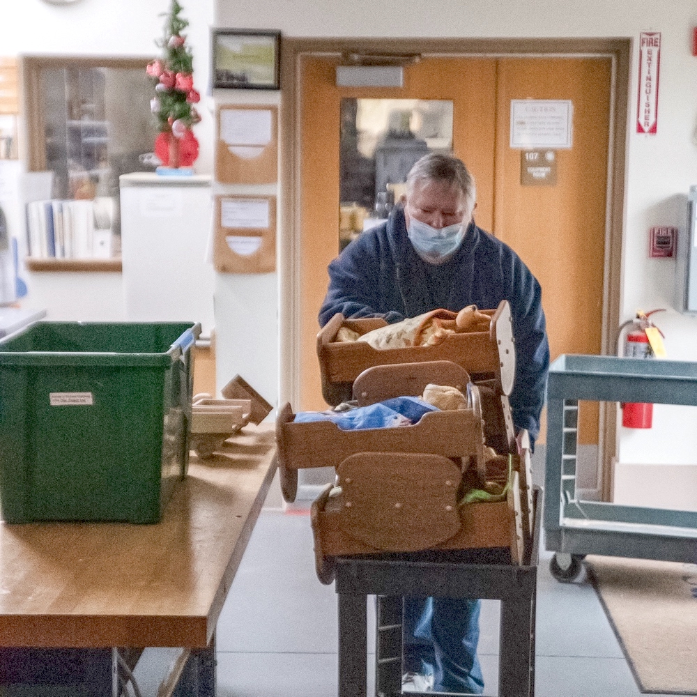 Mike Mulroe wheels out a stack of handcrafted toy cradles.