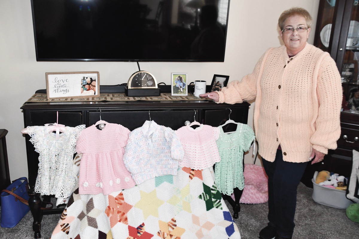 Candi Thuringer wears the crochet maternity coat her mother made and other handmade keepsakes. (Photo by Christine Such/My Sun Day News)