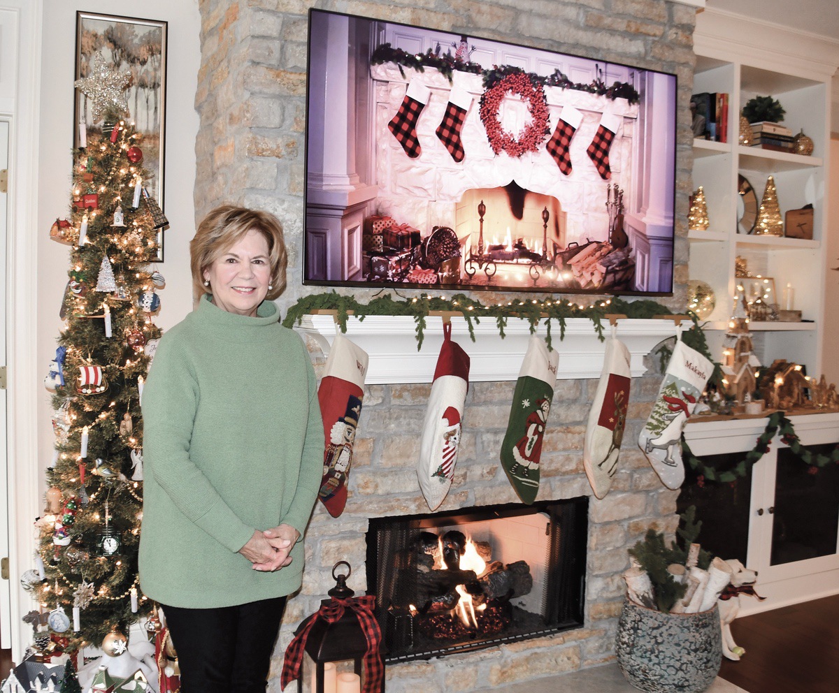 June Vedder poses beside one of her Christmas trees and her fireplace adorned with hung stockings. (Photos by Christine Such/My Sun Day News)